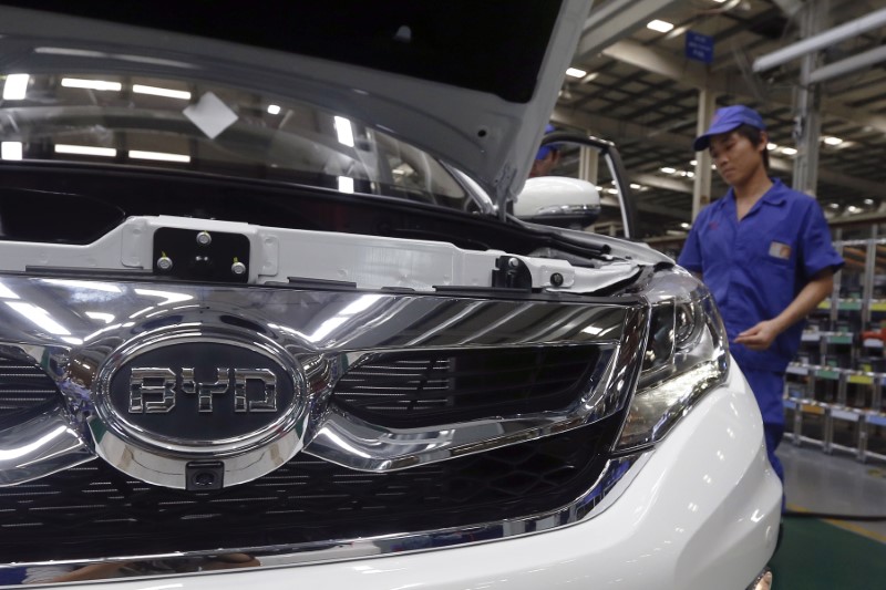 © Reuters. A worker stands behind a car manufactured at a BYD assembly line in Shenzhen