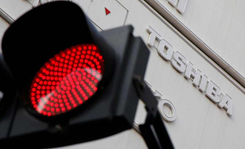© Reuters. A logo of Toshiba Corp is seen behind a red light signal outside an electronics retail store in Tokyo
