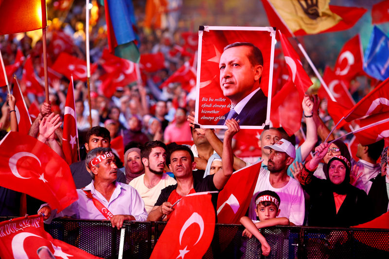 © Reuters. FILE PHOTO: Supporters of Turkish President Erdogan wave national flags as they listen to him through a giant screen in Istanbul's Taksim Square
