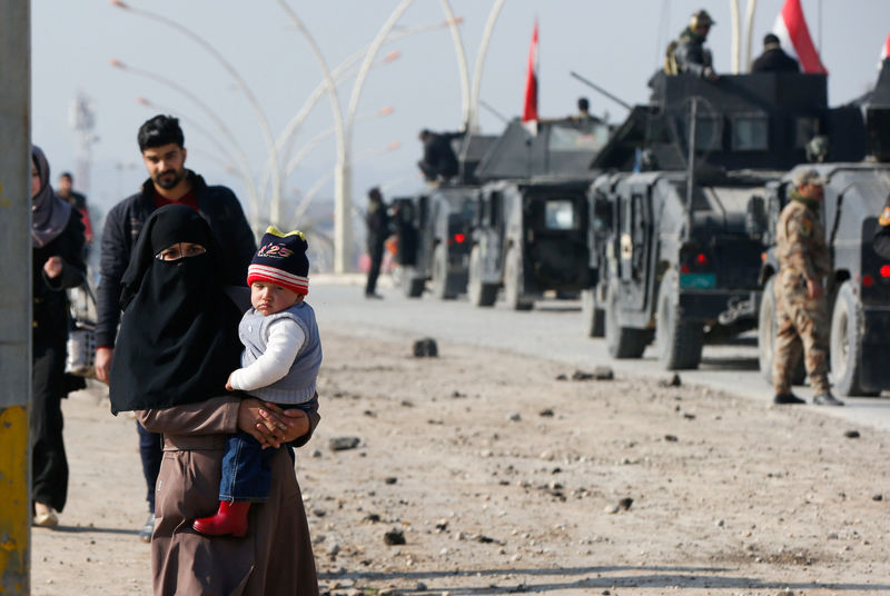 © Reuters. A woman carries her daughter as the civilians leave the city to escape from clashes during a battle with Islamic State militants, in al-Zirai district in Mosul