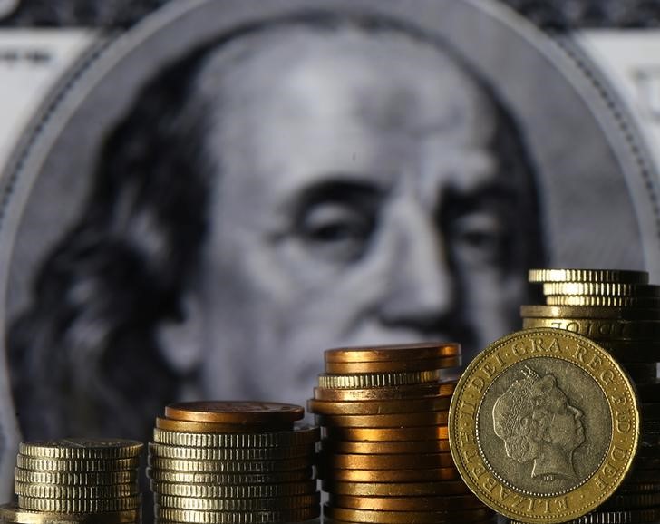 © Reuters. Монеты фунта стерлингов на фоне стодолларовой купюры