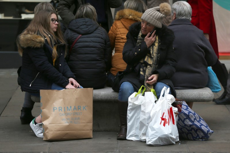 © Reuters. FILE PHOTO -  Shoppers rest on a bench with their bags on Oxford Street in London