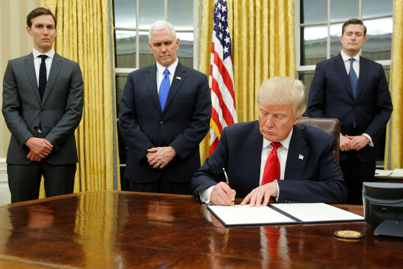 © Reuters. Trump, flanked by Kushner, Pence and Porter, welcomes reporters into the Oval Office for him to sign his first executive orders at the White House in Washington