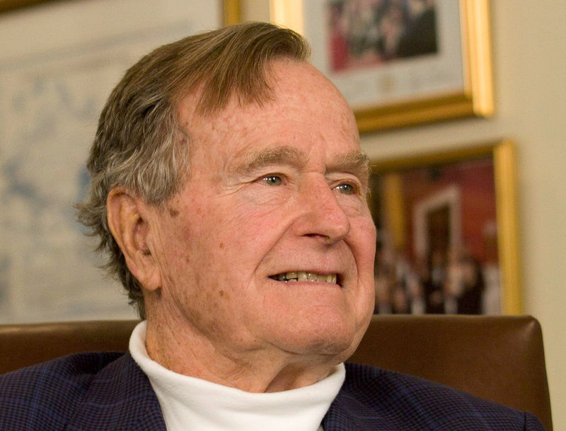 © Reuters. FILE PHOTO -  File photo of former President Bush smiling as he listens to Republican presidential candidate Romney speak in Houston