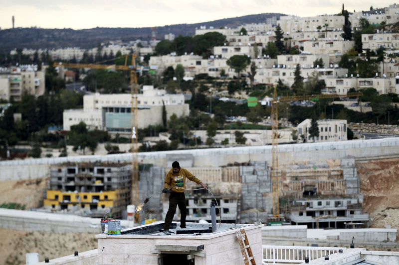 © Reuters. FILE PHOTO: A man works on a roof in Ramat Shlomo, a religious Jewish settlement in an area of the occupied West Bank that Israel annexed to Jerusalem