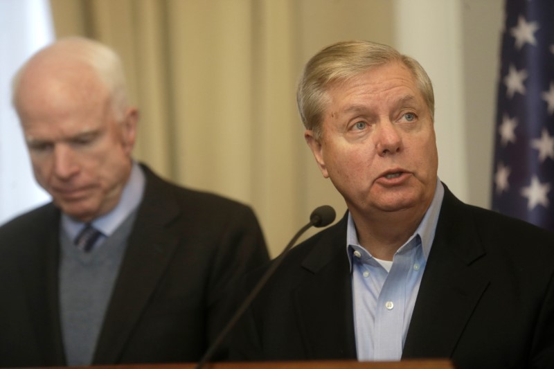 © Reuters. U.S. Senator McCain listens as Senator Graham speaks during a news conference in Riga