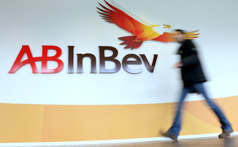 © Reuters. A man walks past the logo of Anheuser-Busch InBev at the brewer's headquarters in Leuven