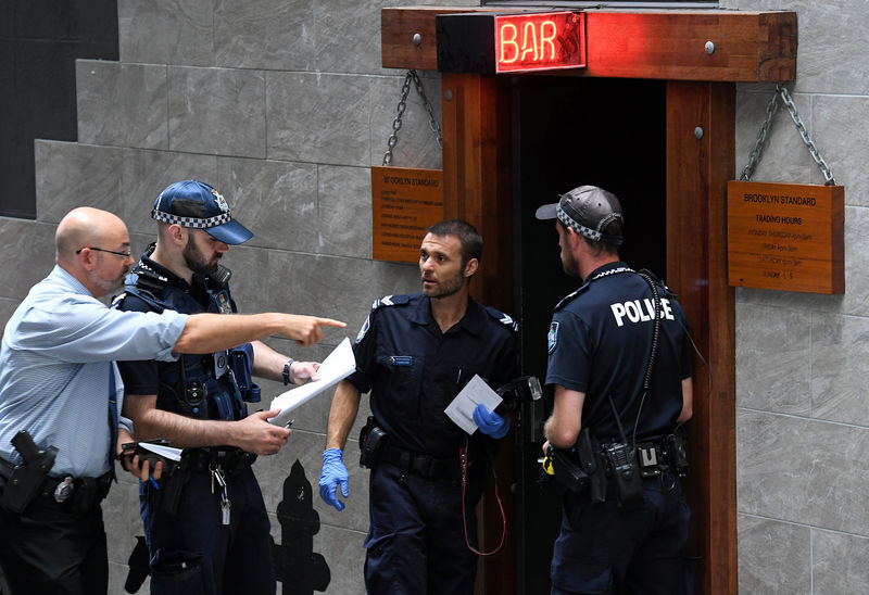 © Reuters. Australian police talk outside a bar as they investigate whether live firearms were used in the filming of a music video during which an actor was fatally wounded in the chest in Brisbane, Australia