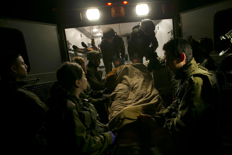 © Reuters. Israeli soldiers transfer a wounded Syrian into an Israeli military ambulance, to give him initial medical treatment, near the Syrian-Israeli border, in the Israeli-occupied Golan Heights
