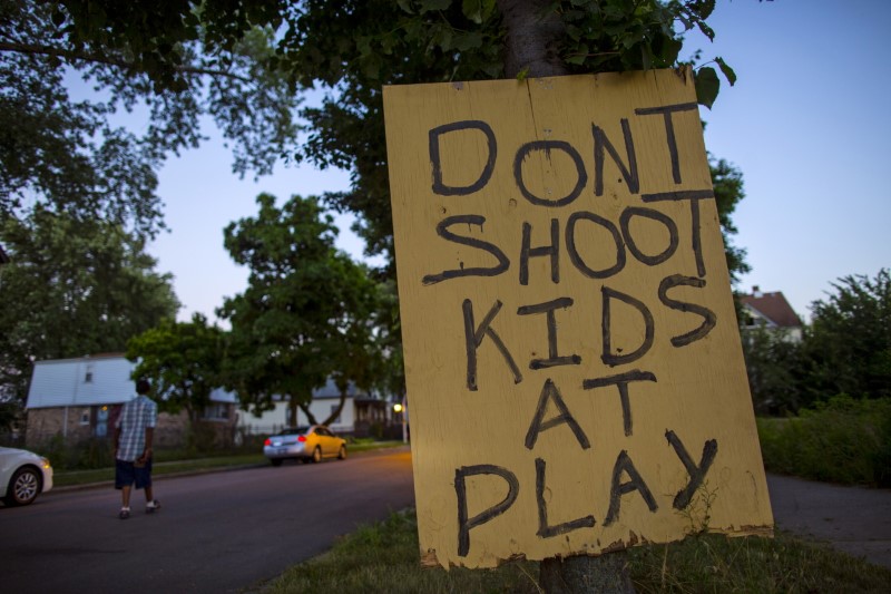 © Reuters. A man walks down a street past a handmade sign posted in the Englewood neighborhood in Chicago