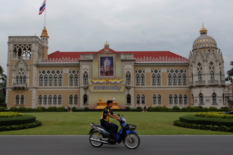 © Reuters. A police officer rides his motorcycle past a picture of Thailand's King Maha Vajiralongkorn Bodindradebayavarangkun installed at the Government House in Bangkok