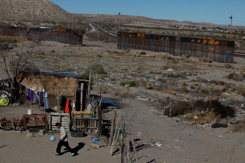 © Reuters. A child plays with a ball at his house as a newly built section of the U.S.-Mexico border fence is seen in the background at Anapra neighbourhood in Ciudad Juarez