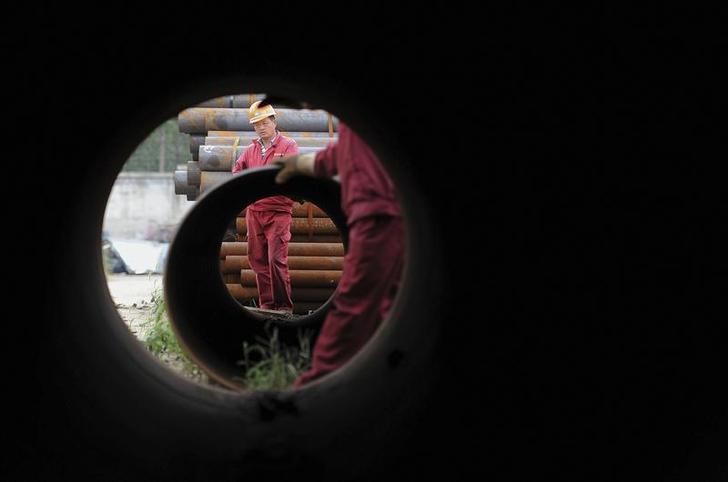 © Reuters. Workers are seen through a steel tube at a steel products market in Hefei