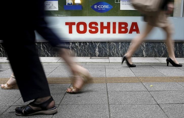 © Reuters. Pedestrians walk past a logo of Toshiba Corp outside an electronics retailer in Tokyo