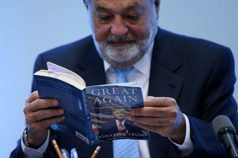 © Reuters. Mexican billionaire Carlos Slim reads the book "Crippled America: How to make America great again" by Donald Trump  during a news conference in Mexico City