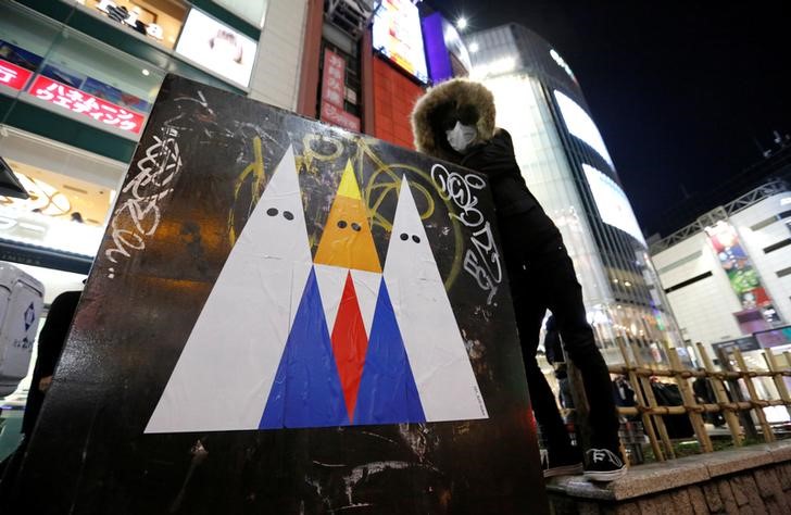 © Reuters. فنان جرافيتي ياباني يرسم ملصقا يستهدف ترامب