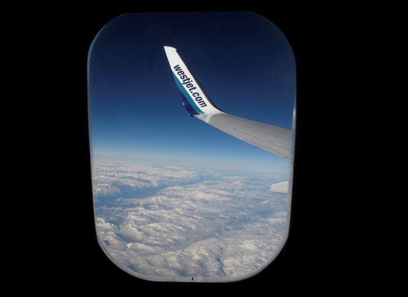 © Reuters. Snow covered mountains are seen under the wing of a WestJet commercial flight on route from Vancouver to Calgary