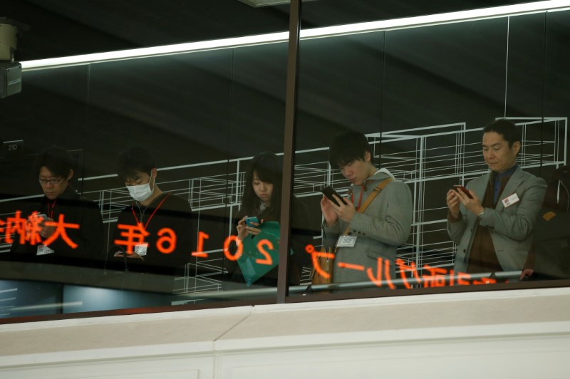 © Reuters. Visitors use their mobile phones before a ceremony marking the end of trading in 2016 at TSE in Tokyo