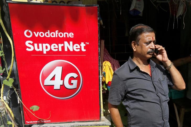© Reuters. A man speaks on his mobile phone next to a Vodafone advertisement in Kolkata