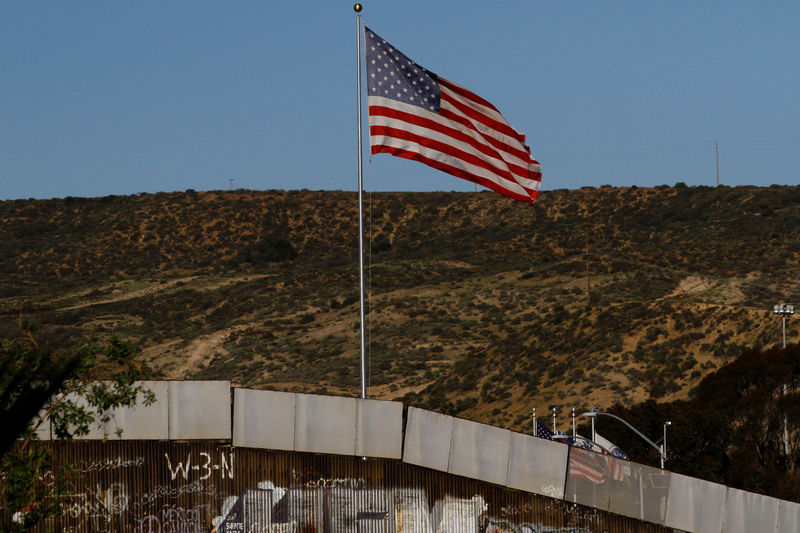 © Reuters. A U.S. flag is seen next to a section of the wall separating Mexico and the United States, in Tijuana
