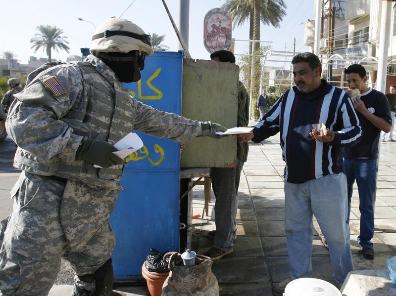 © Reuters. Masked translator for US soldiers distributes peace pamphlets in Baghdad