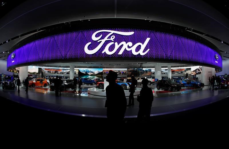 © Reuters. People walk by the Ford display during the North American International Auto Show in Detroit