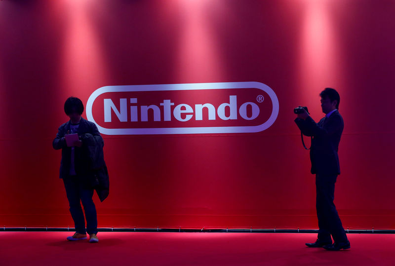 © Reuters. FILE PHOTO -  People stand in front of Nintendo's logo at the presentation ceremony of its new game console Switch in Tokyo