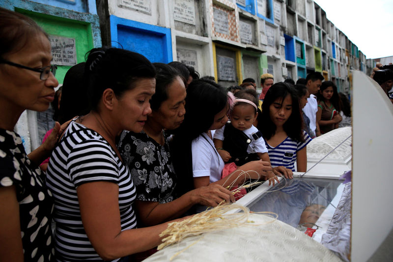 © Reuters. Loved ones and mourners pay their respects to the bodies of Maximo Pepito and his brother Marlon Pepito, victims of a summary execution by unknown assailants related to the drug war, during their funeral at the Navotas cemetery, north of Metro Manila