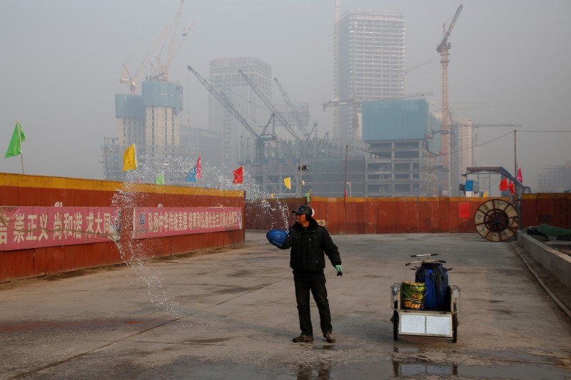 © Reuters. A worker sprinkles water onto a road at a construction site in Beijing,