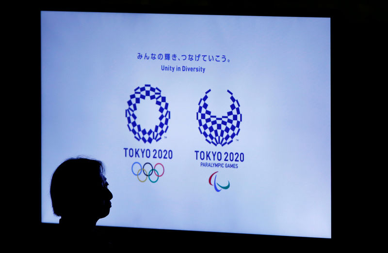 © Reuters. FILE PHOTO: A woman is silhouetted against a monitor showing Tokyo 2020 Olympics and Paralympics emblems during the Olympic and Paralympic flag-raising ceremony at Tokyo Metropolitan Government Building in Tokyo