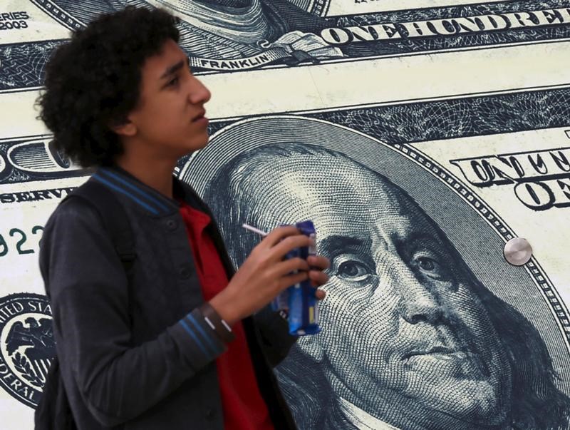 © Reuters. A boy walks past an exchange bureau advertisement showing images of the U.S dollar in Cairo