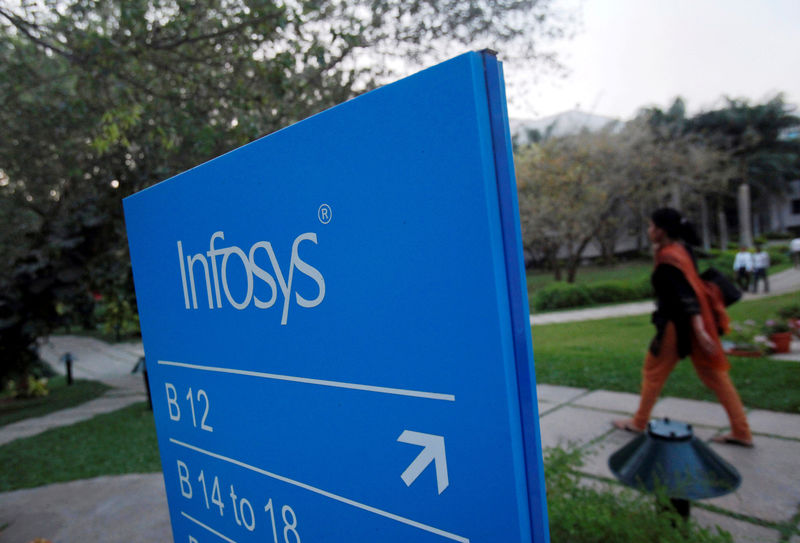 © Reuters. FILE PHOTO -  An employee walks past a signage board in the Infosys campus at the Electronics City IT district in Bengaluru