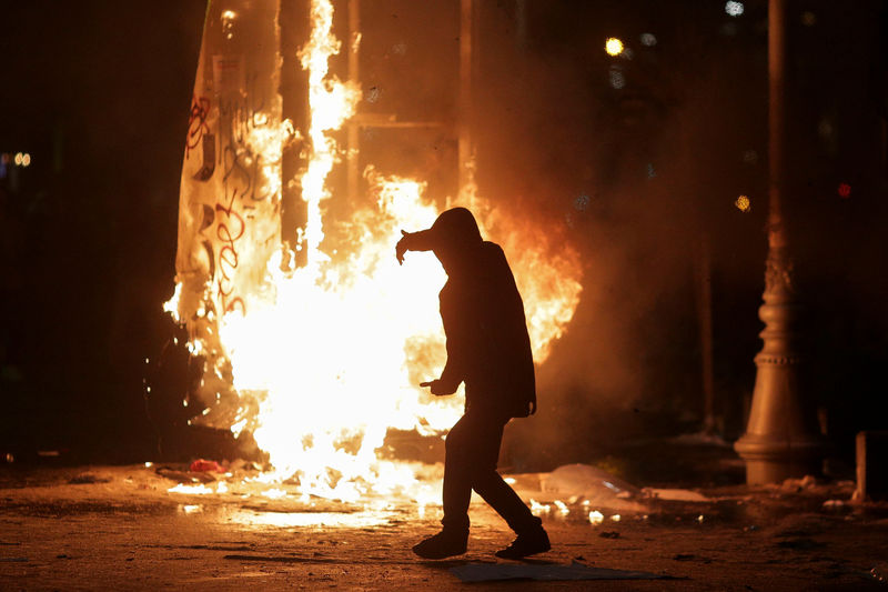 © Reuters. Protester walks in front of a burning street sign during scuffles with police at a demonstration in Bucharest