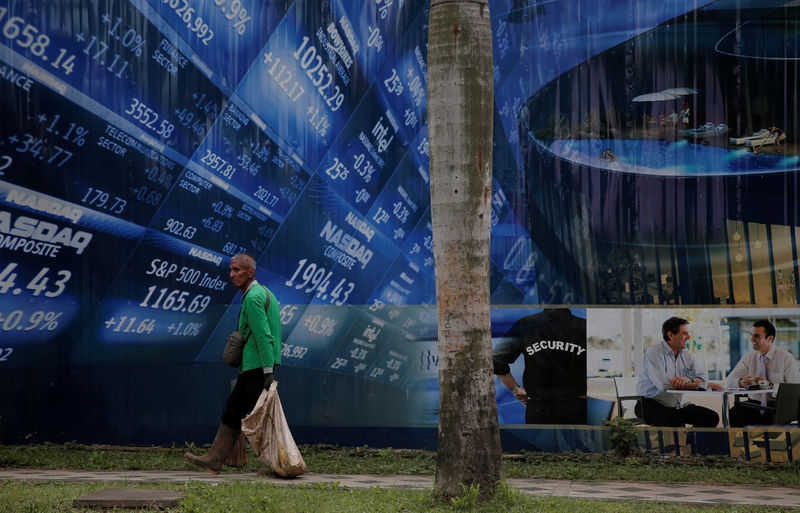 © Reuters. A worker walks in front of a stock market poster at Sudirman Business District compound in Jakarta