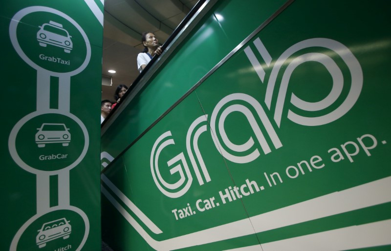 © Reuters. Commuters pass Grab transport booking service app advertisements at a train station in Singapore