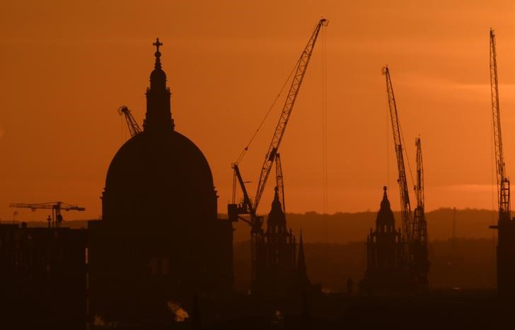 © Reuters. Construction cranes are seen by St Paul's cathedral at dawn in London