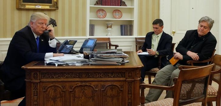 © Reuters. Trump, seated with Flynn and Bannon, speaks by phone with Turnbull in the Oval Office at the White House