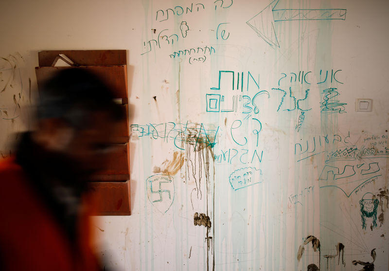 © Reuters. A man walks past a wall of a synagogue covered with text and graffiti during the second day of an operation by Israeli forces to evict the illegal outpost of Amona