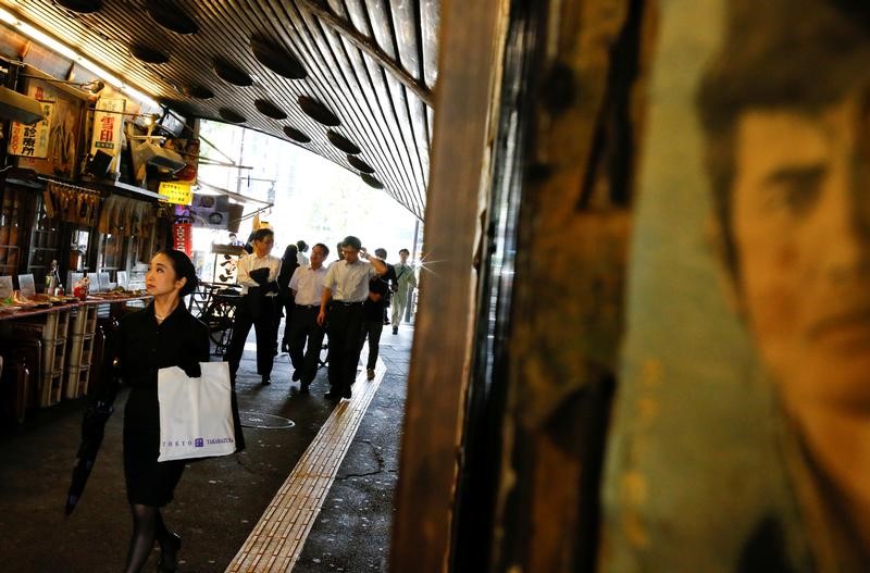 © Reuters. People walk past a restaurant under a railway arch in a business district in Tokyo