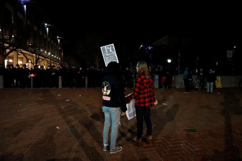 © Reuters. Demonstrators hold signs as they face a police line after a student protest turned violent at UC Berkeley during a demonstration over right-wing speaker Yiannopoulos, who was forced to cancel his talk, in Berkeley