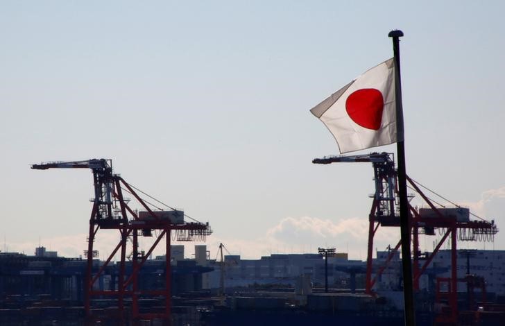 © Reuters. Japan's national flag is seen in front of containers and cranes at an industrial port in Tokyo