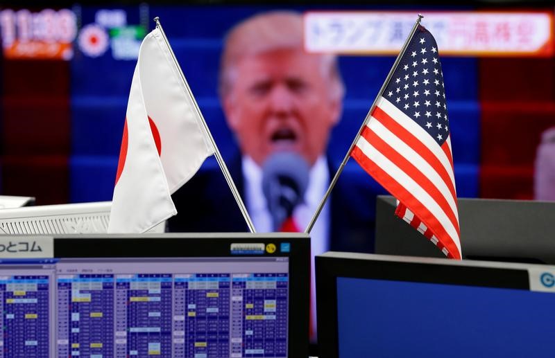 © Reuters. National flags of Japan and the U.S. are seen in front of a monitor showing U.S. President Donald Trump at a foreign exchange trading company in Tokyo