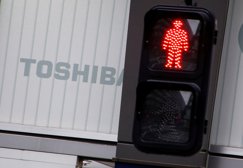 © Reuters. FILE PHOTO -  Toshiba's logo is seen behind a traffic sign at an electronic shop in Tokyo