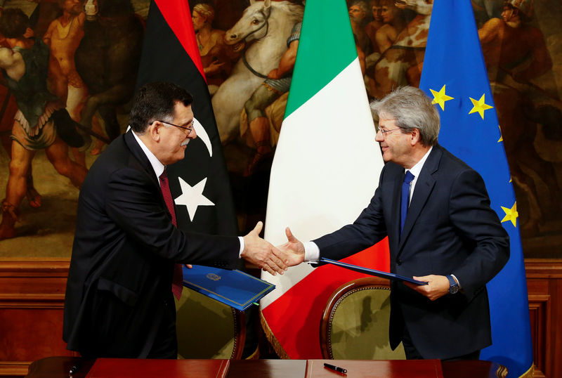 © Reuters. Italian Prime Minister Paolo Gentiloni and his Libyan counterpart Fayez al-Sarraj shake hands after signing a bilateral agreement during a meeting at Chigi Palace in Rome