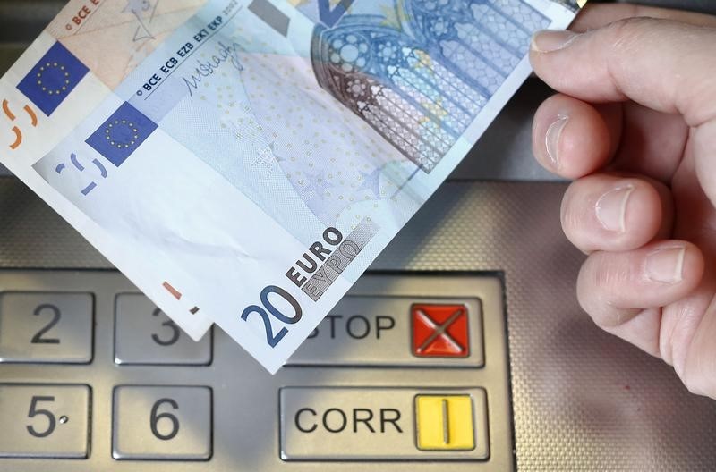 © Reuters. A woman holds a 20 and 50 Euro bank notes in front of an ATM in this illustration picture taken in Bern
