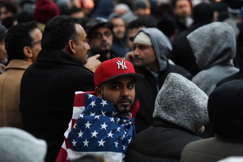 © Reuters. Mohammed Abdul wraps himself in an American flag before a prayer session during a protest by the Yemeni community against U.S. President Donald Trump's travel ban in the Brooklyn borough of New York City