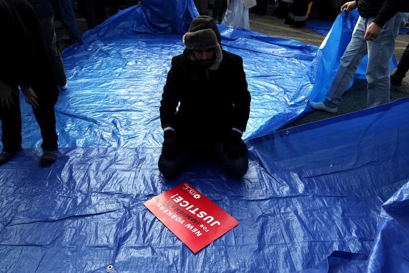 © Reuters. A man participates in prayers during an interfaith action and the Jummah prayer outside Terminal 4 at John F. Kennedy Airport in New York