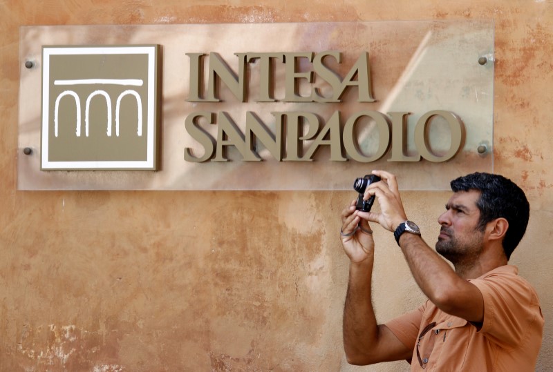 © Reuters. FILE PHOTO: A man takes a picture in front of Intesa Sanpaolo bank in downtown Rome