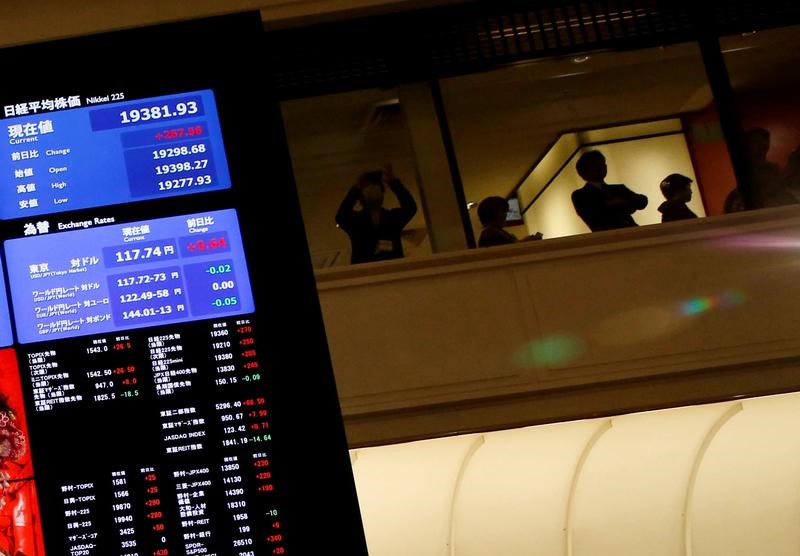 © Reuters. People are seen behind an electronic board showing stock prices after the New Year opening ceremony at the Tokyo Stock Exchange (TSE), held to wish for the success of Japan's stock market, in Tokyo