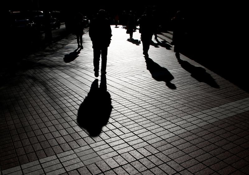 © Reuters. Pedestrians cast shadows as they make their way at a financial district in Tokyo